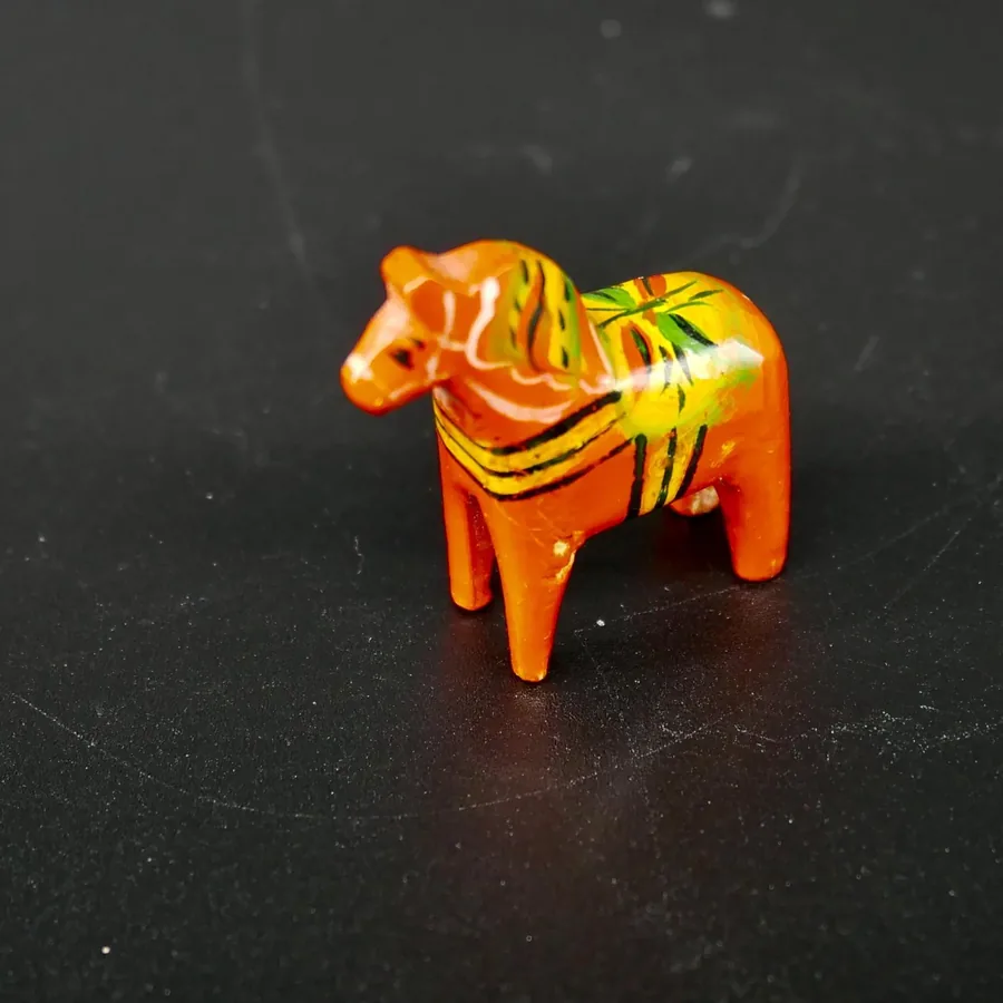 Angled overhead perspective of red wood Dala horse showing curved back and decorative painted blanket pattern in natural ligh