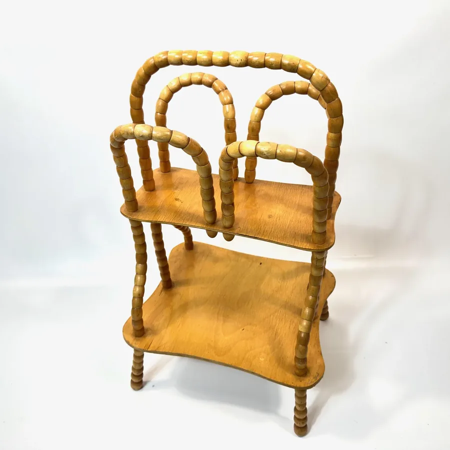 Angled perspective displaying rotating bead frame detail and wooden shelf construction of mid-century storage piece