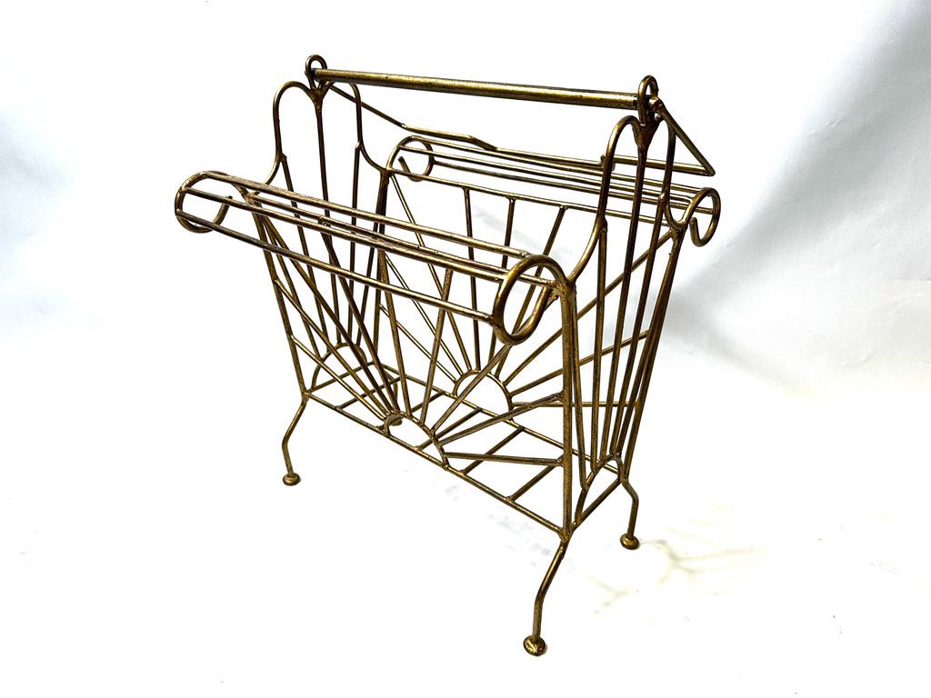 Antique gold iron magazine rack with radial wire design, ball feet, and curved handles, three-quarter view
