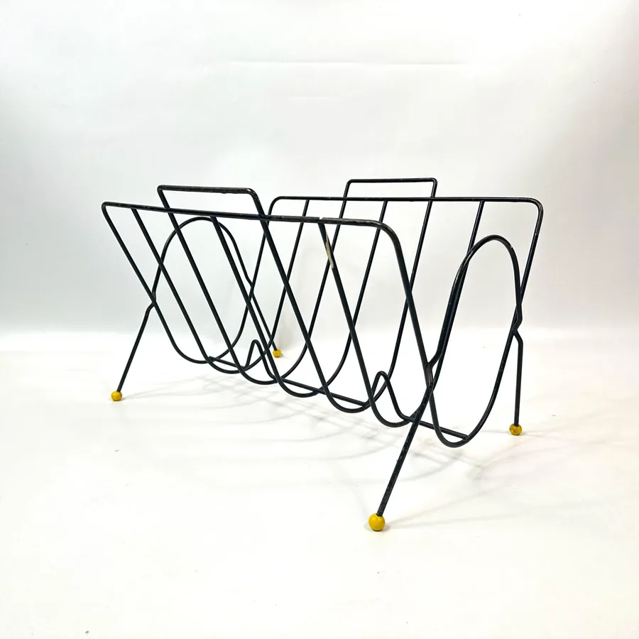 Atomic magazine rack side profile showing architectural wire loops and curved supports with yellow feet details