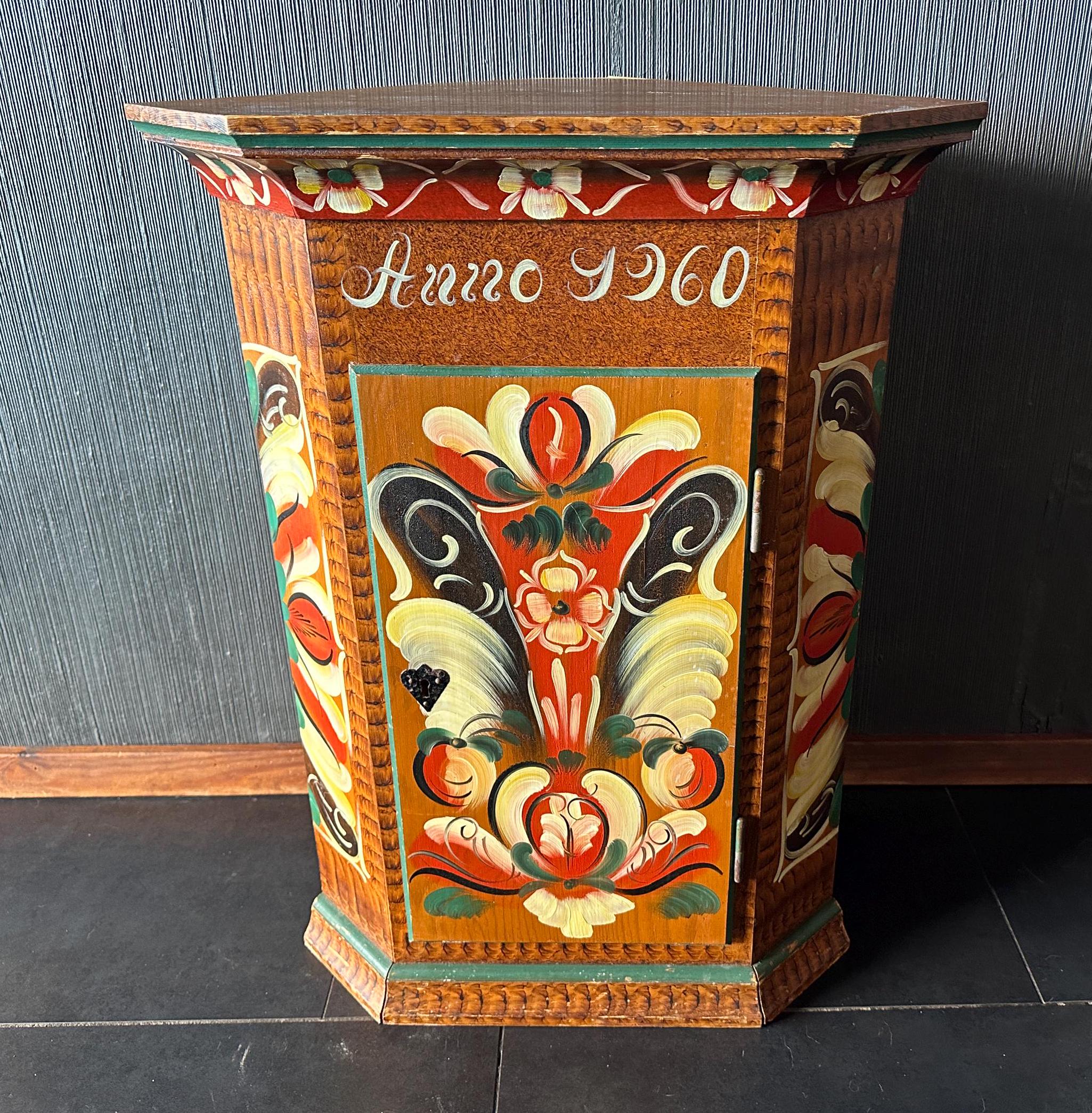 Back-angled view of painted Swedish cupboard showing stepped base, side panel decoration, and overall silhouette against neut