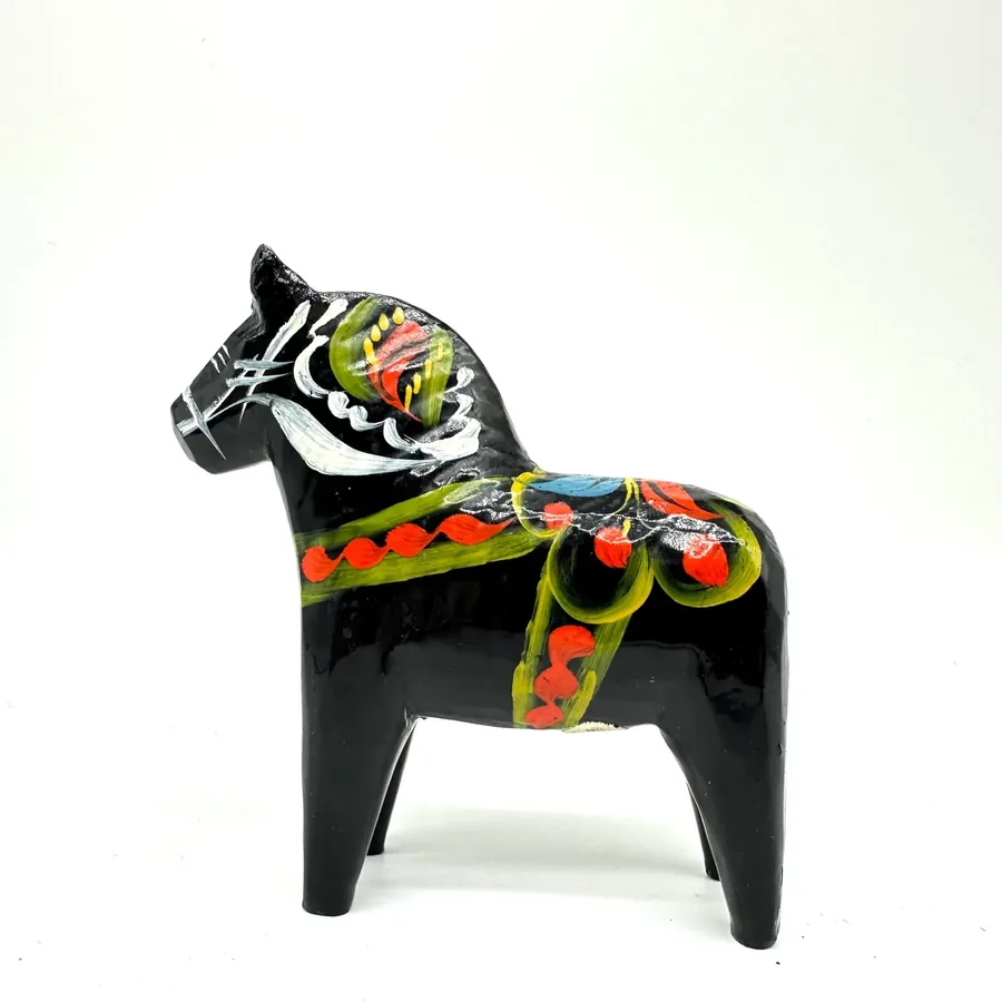 Black painted wooden dala horse with hand-painted multicolored folk-art saddle and bridle, right-side angled view showing ful