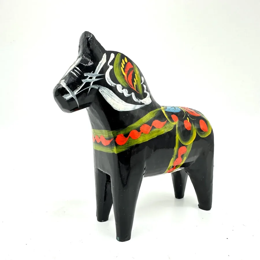 Black wooden dala horse with intricate hand-painted bridle and saddle decoration in primary colors, viewed from forward diago