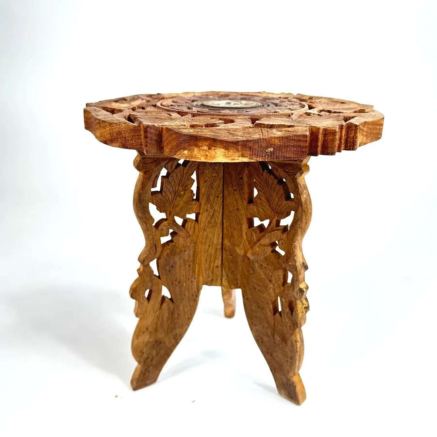 Carved wood tripod plant stand with ornate leaf motifs and folding legs, front-facing view showing intricate details