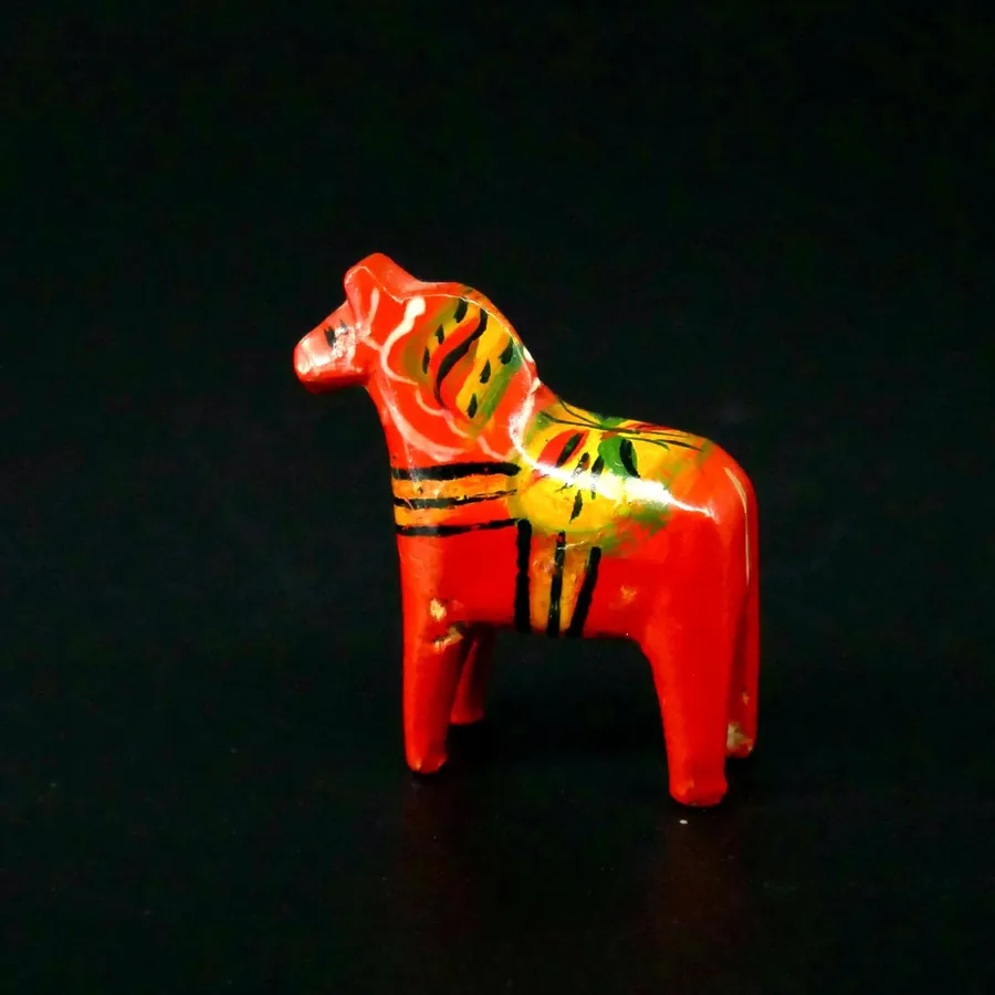 Close angled view of miniature Dala horse emphasizing carved head, neck mane detail and upper body hand-painted decoration