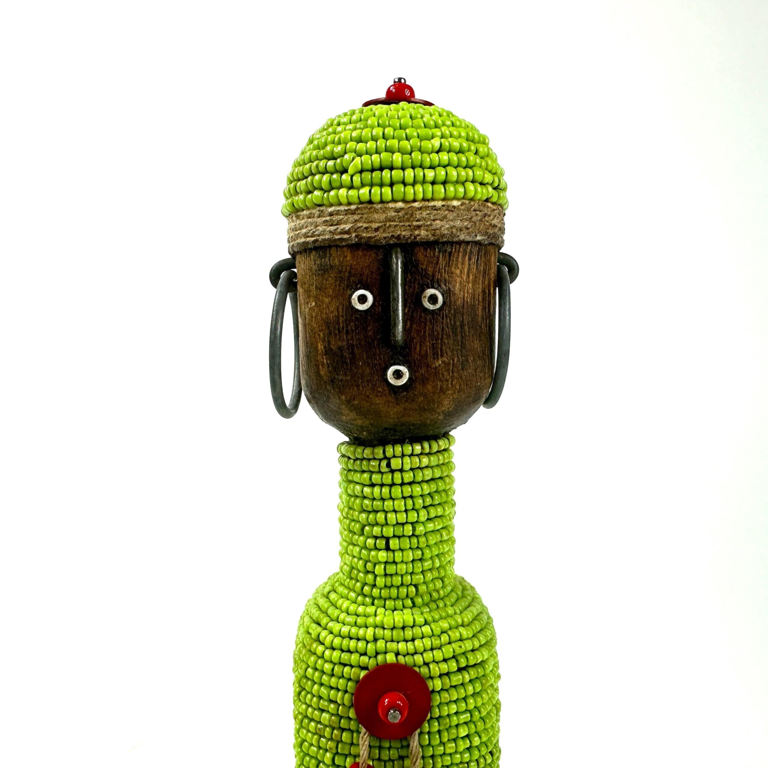 Close-up of carved wooden head with metal wire ear loops and beaded green body detail showing intricate beadwork pattern
