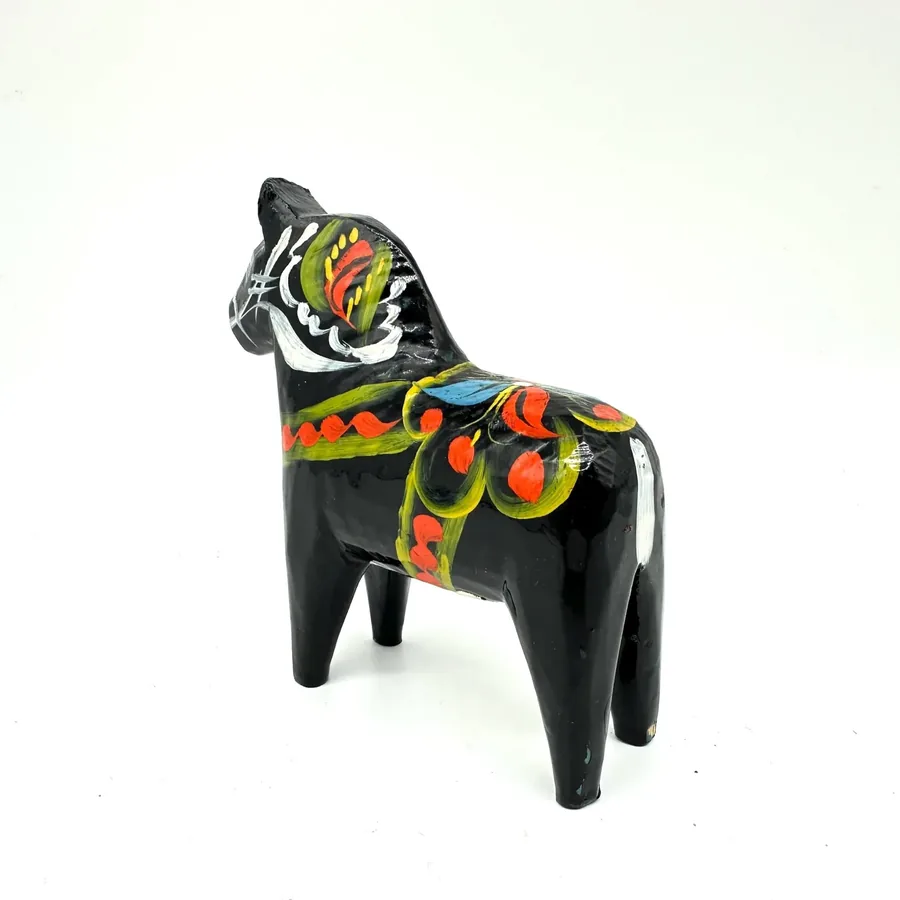 Compact black dala horse figurine with hand-painted saddle showing red and yellow geometric patterns, viewed from distinctive