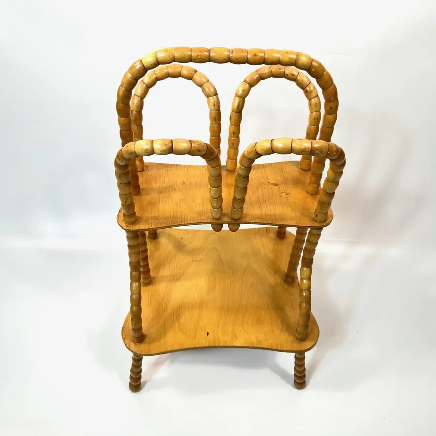 Direct frontal view showing two wooden shelves centered within rotating bead spindle frame of Scandinavian storage piece