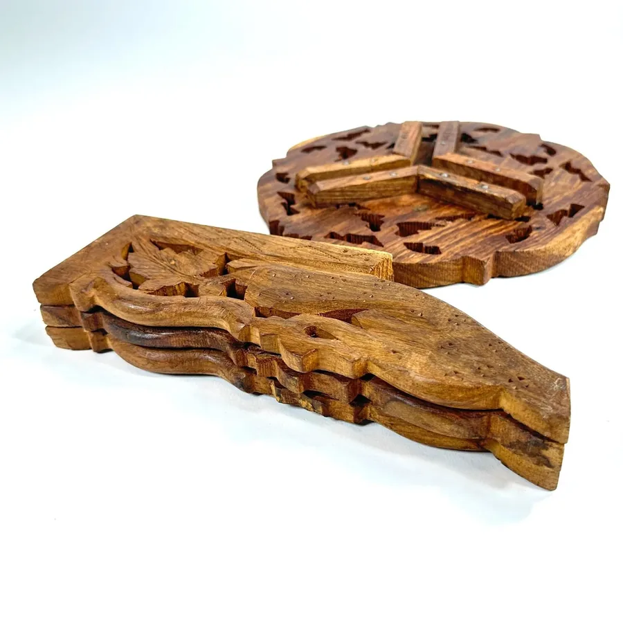 Disassembled wooden tripod leg detail showing individual carved leaf patterns and wood grain texture separately