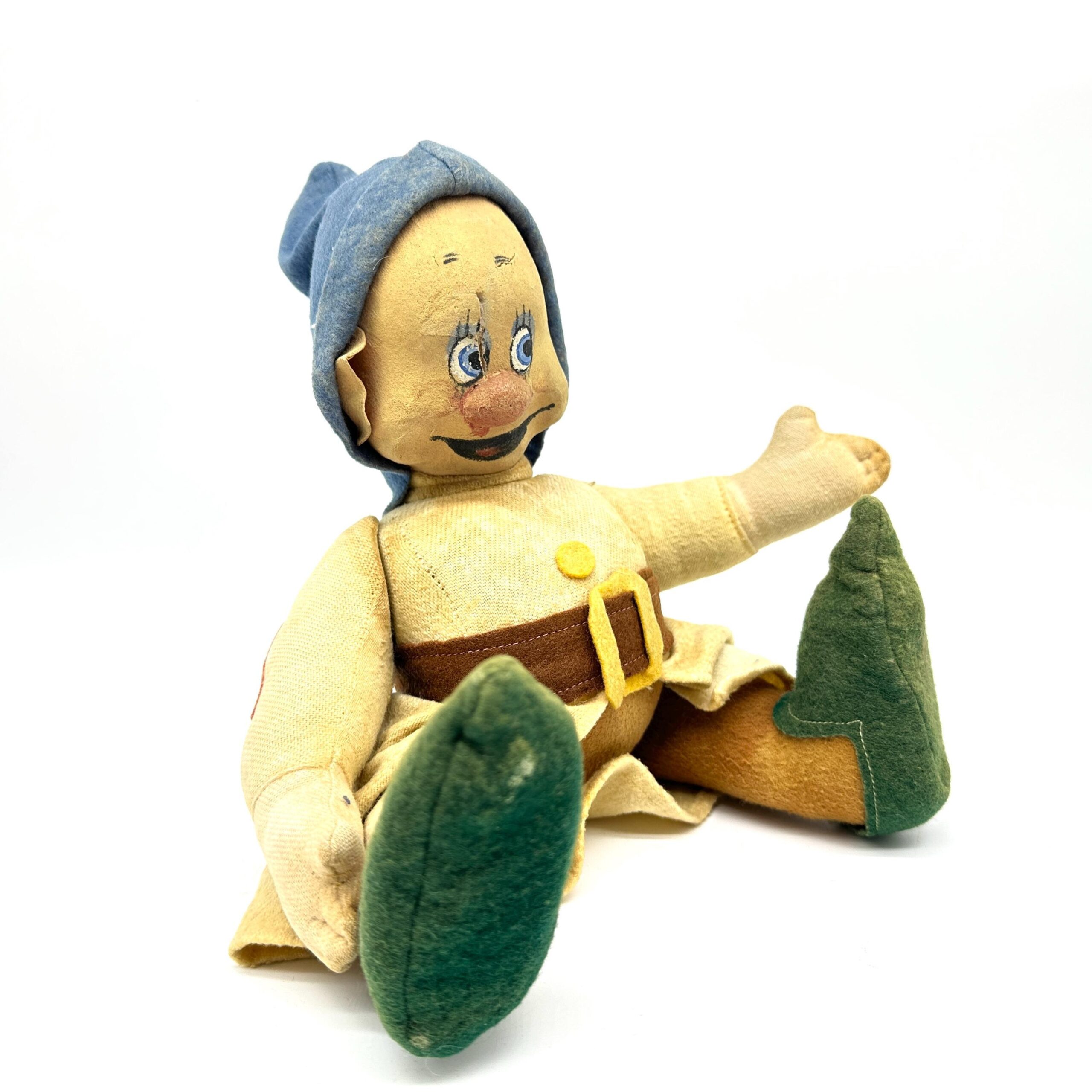 Dwarf doll in extended arm pose with one limb stretched outward, blue hood visible, green boots splayed, yellow dress drapes