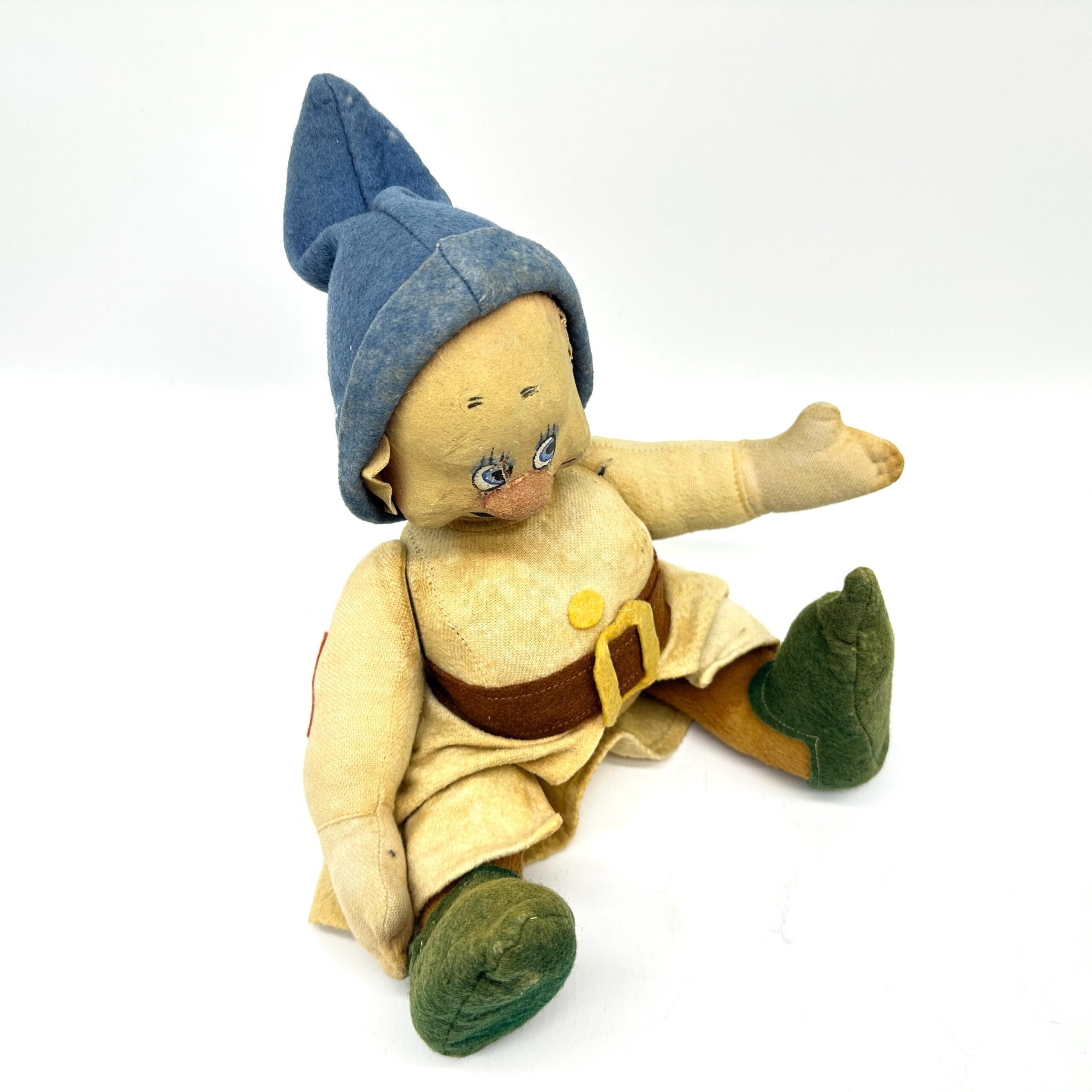 Dwarf doll with one arm extended upward in cheerful pose, blue cloth hood, yellow dress bodice, articulated fingers, green fe
