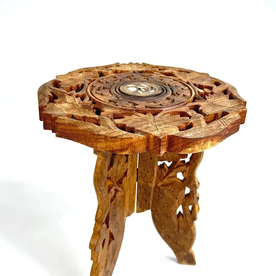 Elevated perspective showing carved wooden top with scalloped borders, central floral detail, and tripod base below