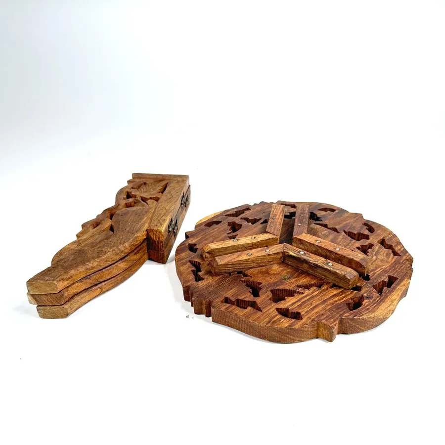 Flat-lay view of separated carved wood components showing tabletop with scalloped edges and folding tripod legs
