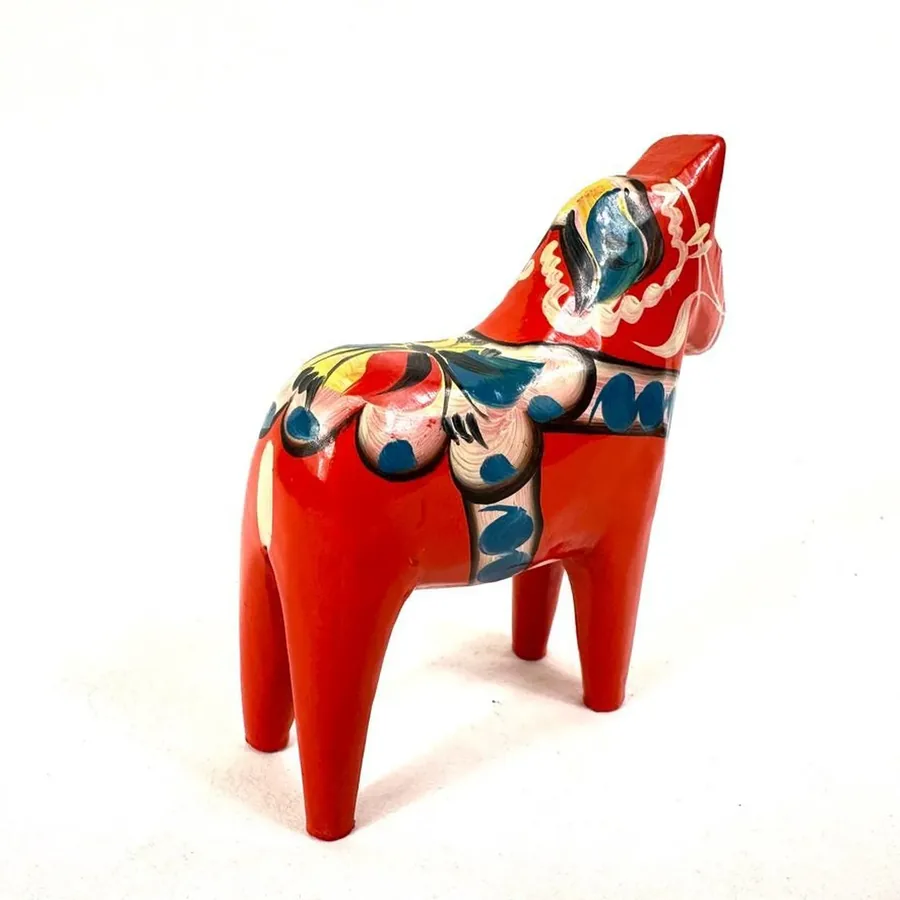 Hand-painted wooden Dala horse from elevated angle, revealing top of head carving and full decorative blanket painting