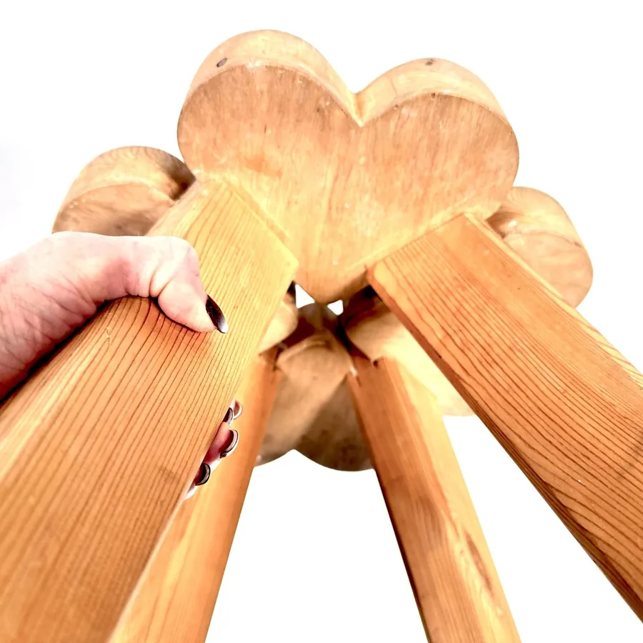 Hands holding wooden stool seat sections showing scale, weight, and solid construction of material