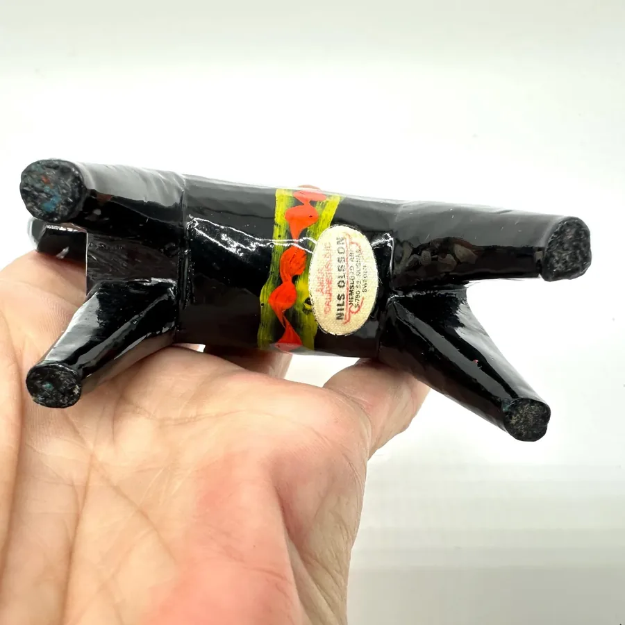 Held in hand, black wooden dala horse showing scale and texture of hand-painted surface with aged varnish patina and folk-art