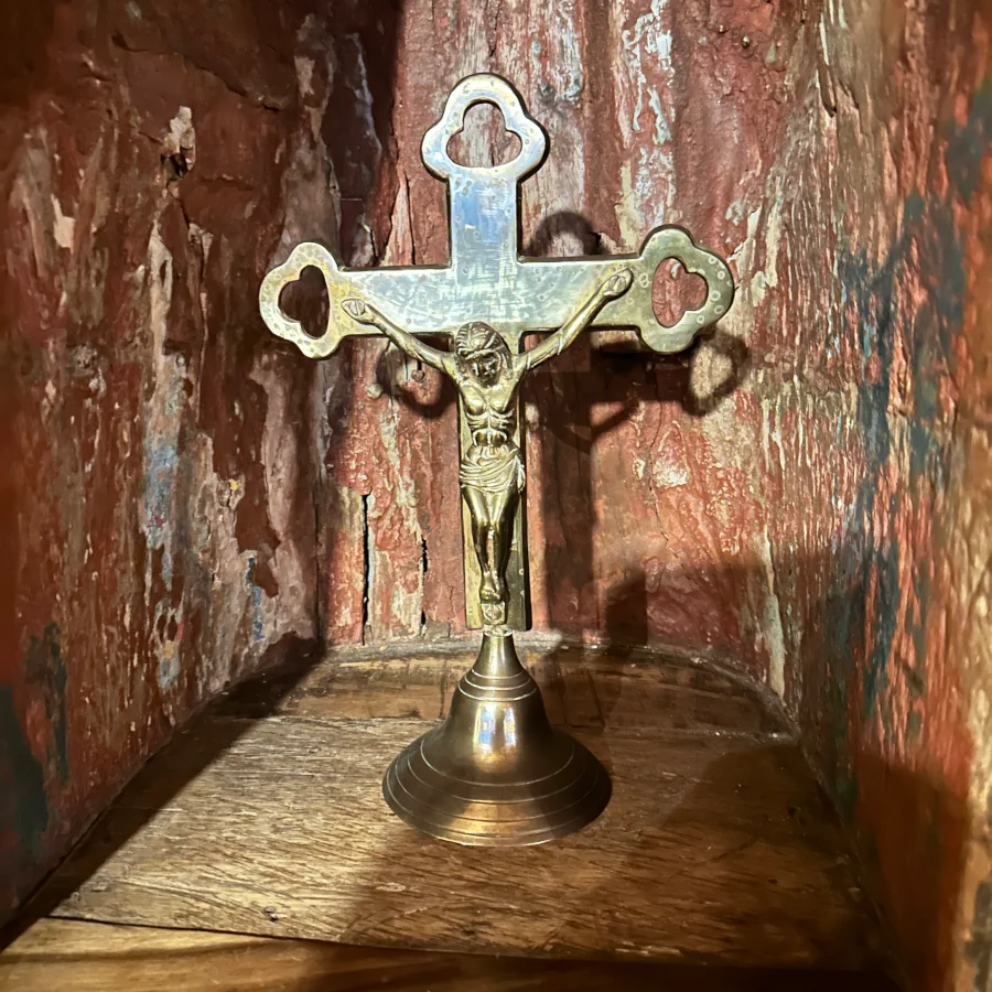 Brass desk cross with blue and white enamel accents resting on aged wooden surface