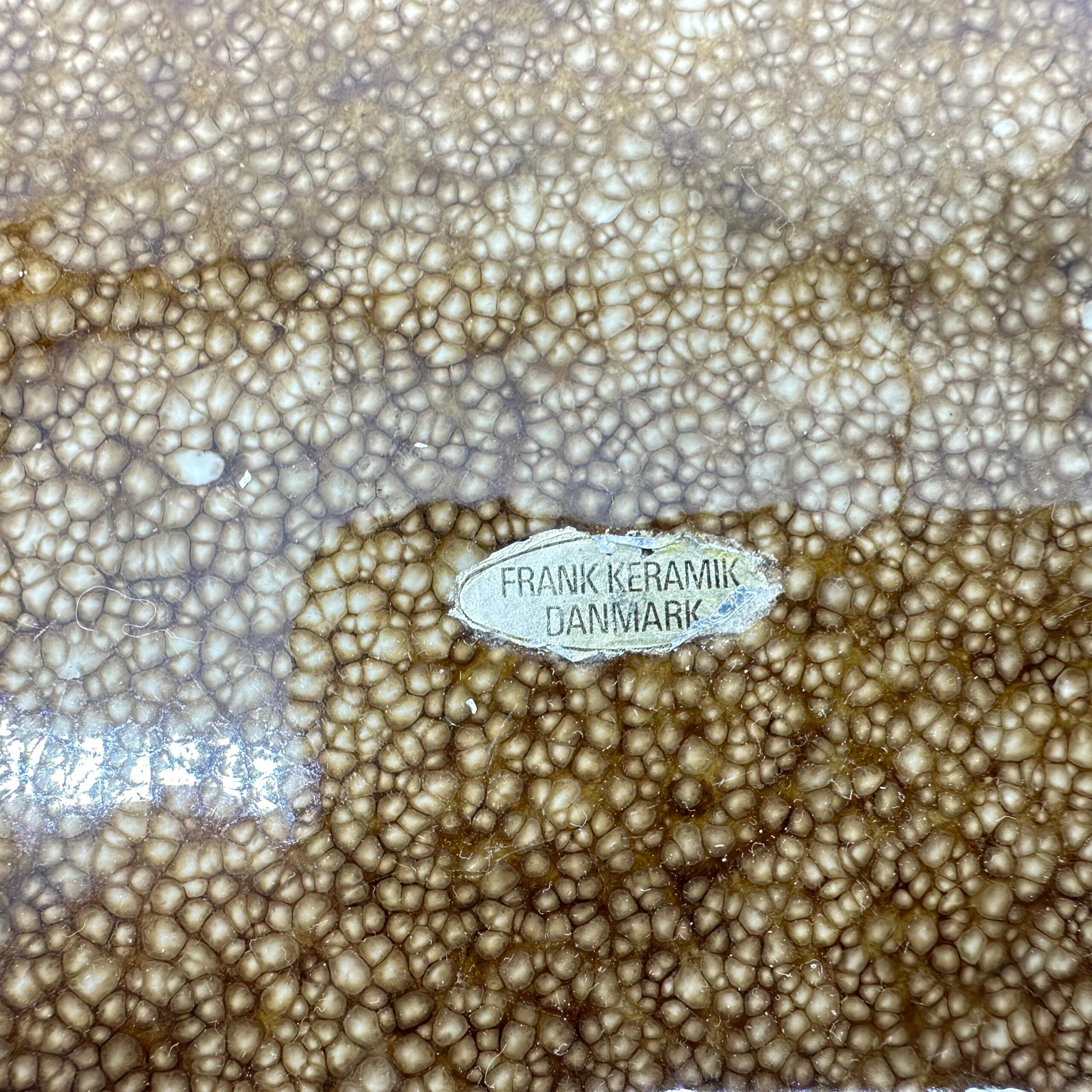 Maker\\\'s mark close-up, Frank Keramik Danmark stamp on bowl base with speckled glaze texture background