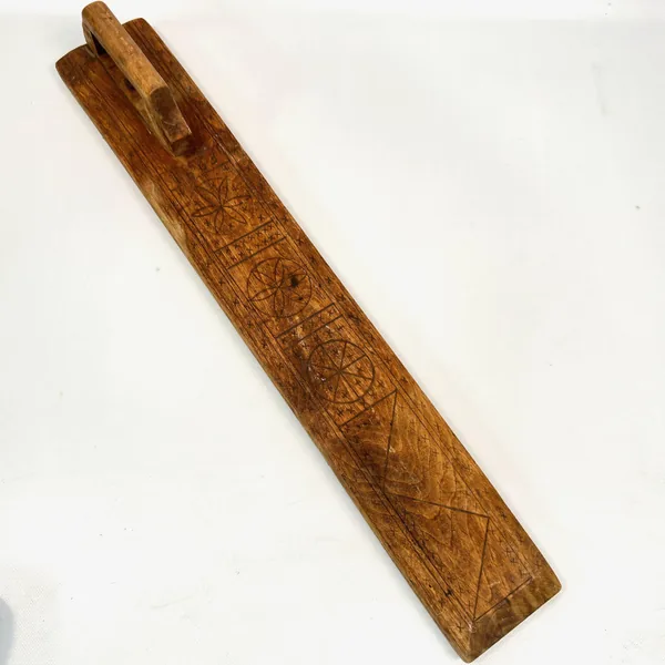 Mangling board angle showing handle configuration, incised border patterns, and depth of wood carving on paddle