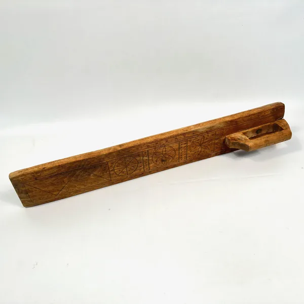 Mangling board angled view showing three-dimensional form, wooden handle silhouette, and weathered surface texture
