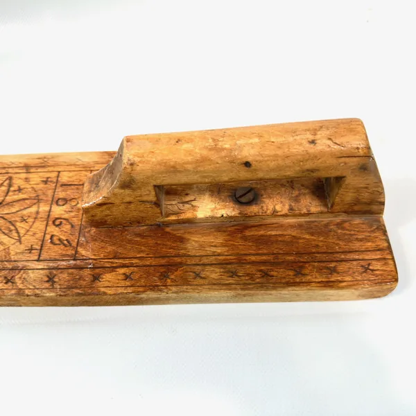 Mangling board handle detail, side angle revealing wooden dowel construction and attachment to carved paddle surface
