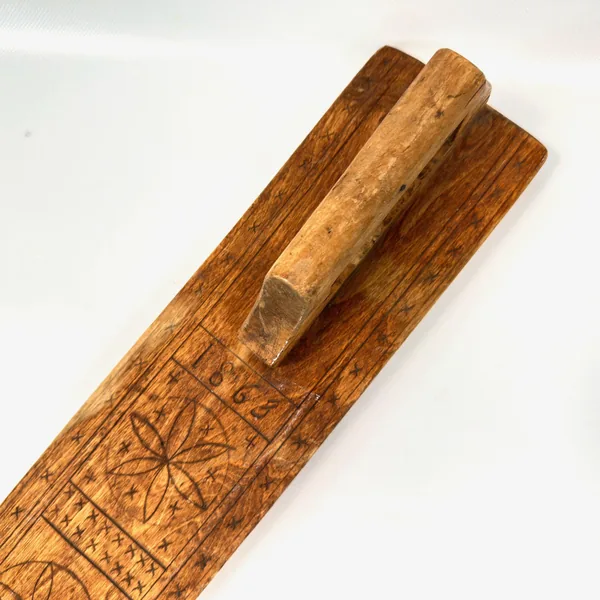 Mangling board handle section with three wooden dowels, showing joinery and decorative border carving detail