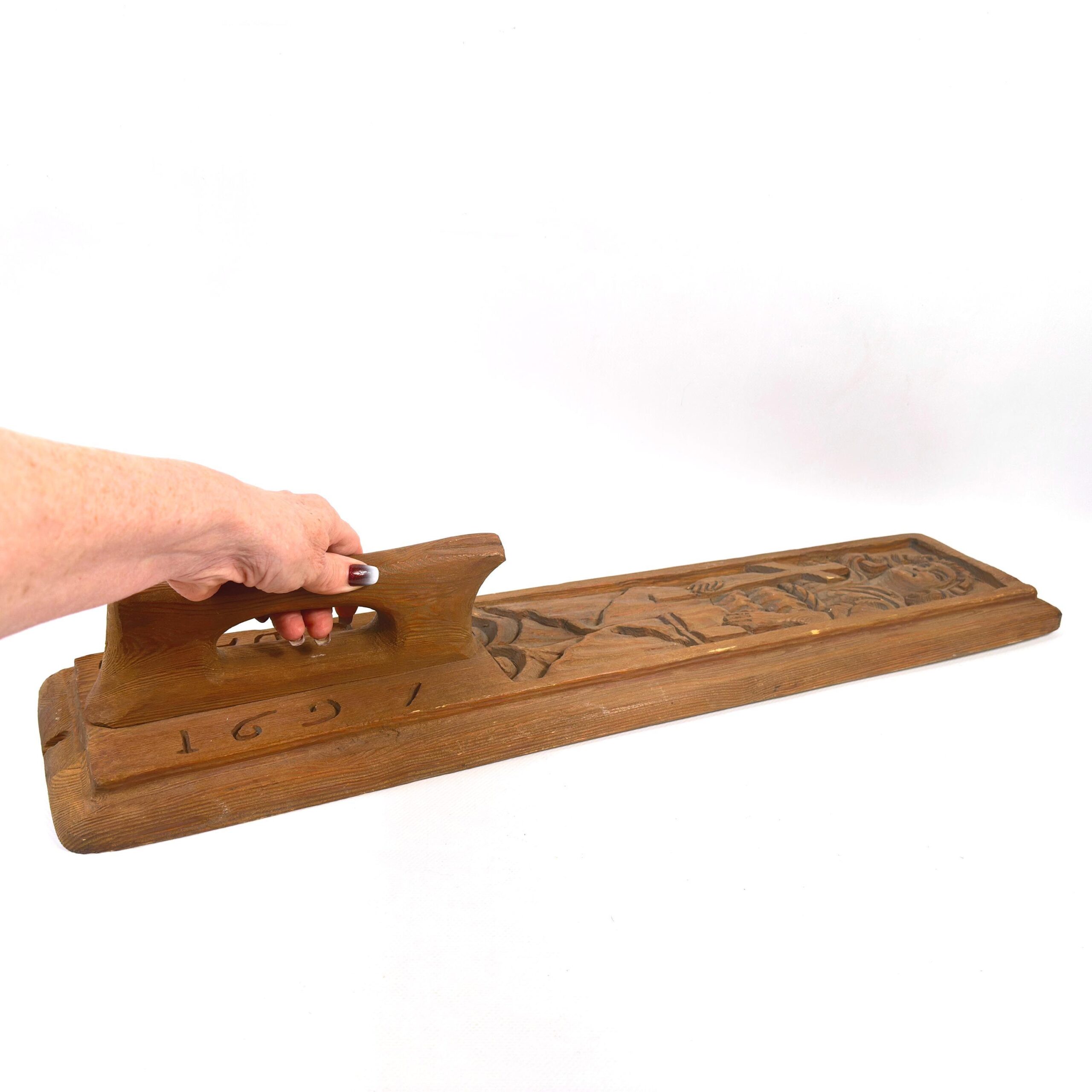 Mangling board in use demonstration with hand grip, showing functional form and carved panel in context