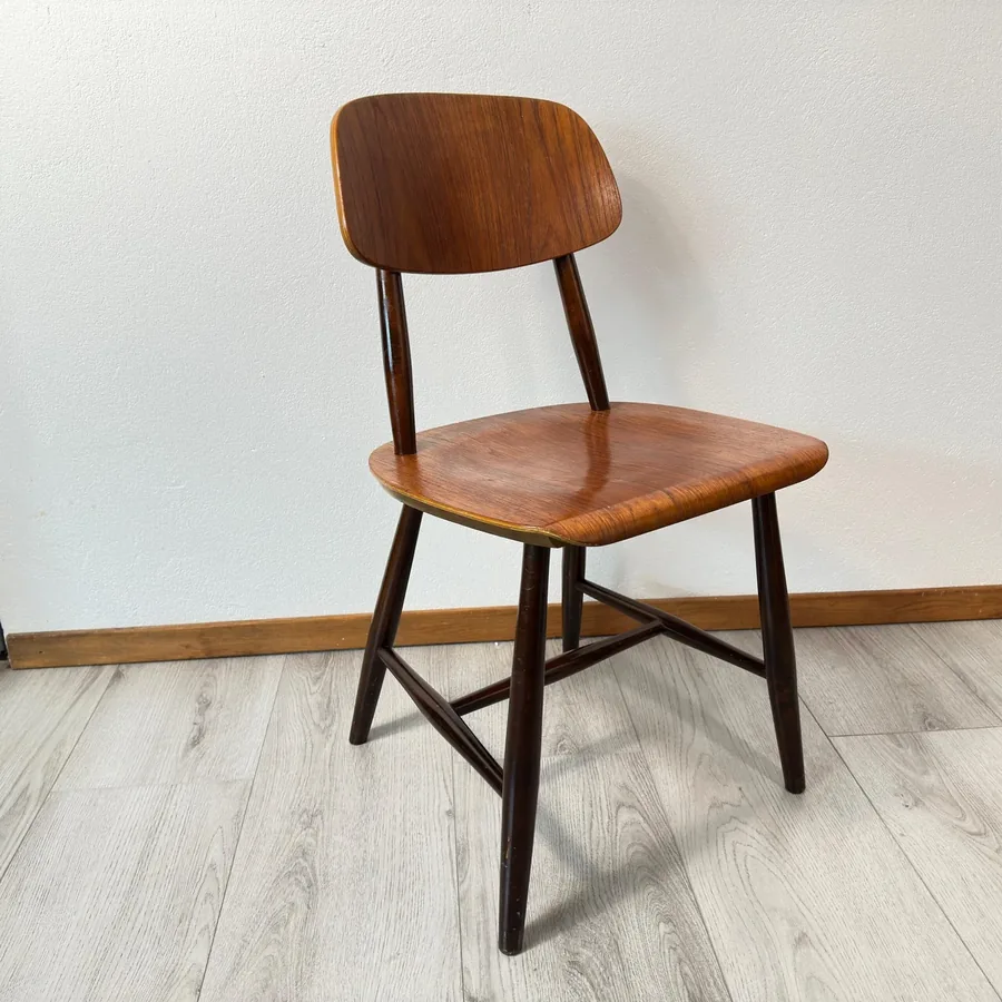 Mid-century Scandinavian dining chair with warm teak veneer seat and back, dark birch frame, shown in full profile view