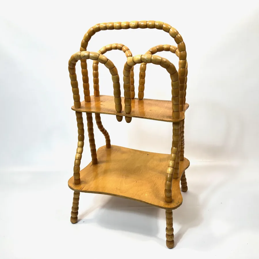 Side profile of vintage wooden magazine holder showing curved bead spindles and stacked timber storage shelves