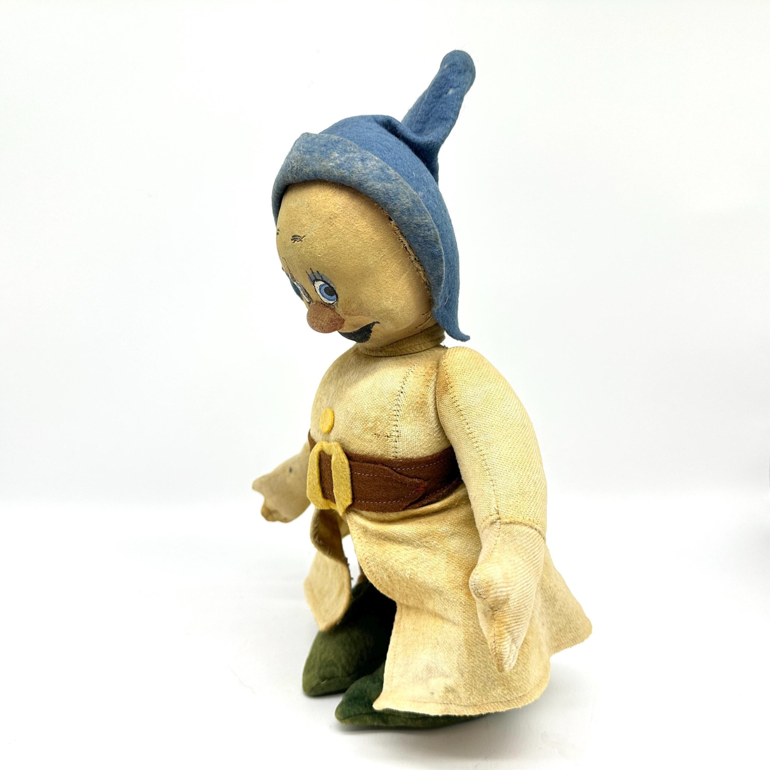 Standing dwarf doll angled view with blue pointed hood, painted facial features, yellow dress with brown trim, green boots pl