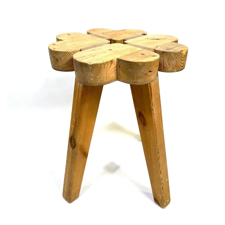 Straight-on view of wooden clover stool showing square profile with rounded edges and angled wooden legs