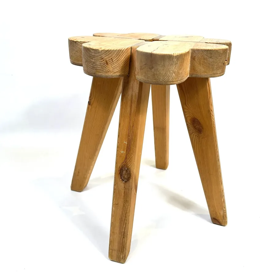 Three-quarter angled view showing wooden stool's solid construction, tapered legs, and aged wood surface texture