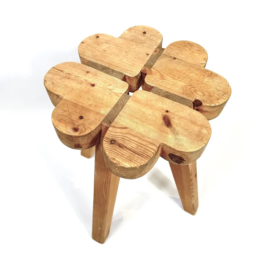 Tilted angle view of wooden clover stool showing three-dimensional form, seat assembly, and leg angles