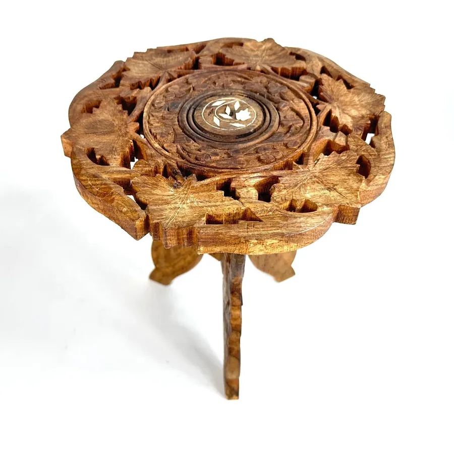 Top-down angle of stand showing floral center inlay and ornate carved borders surrounding the platform