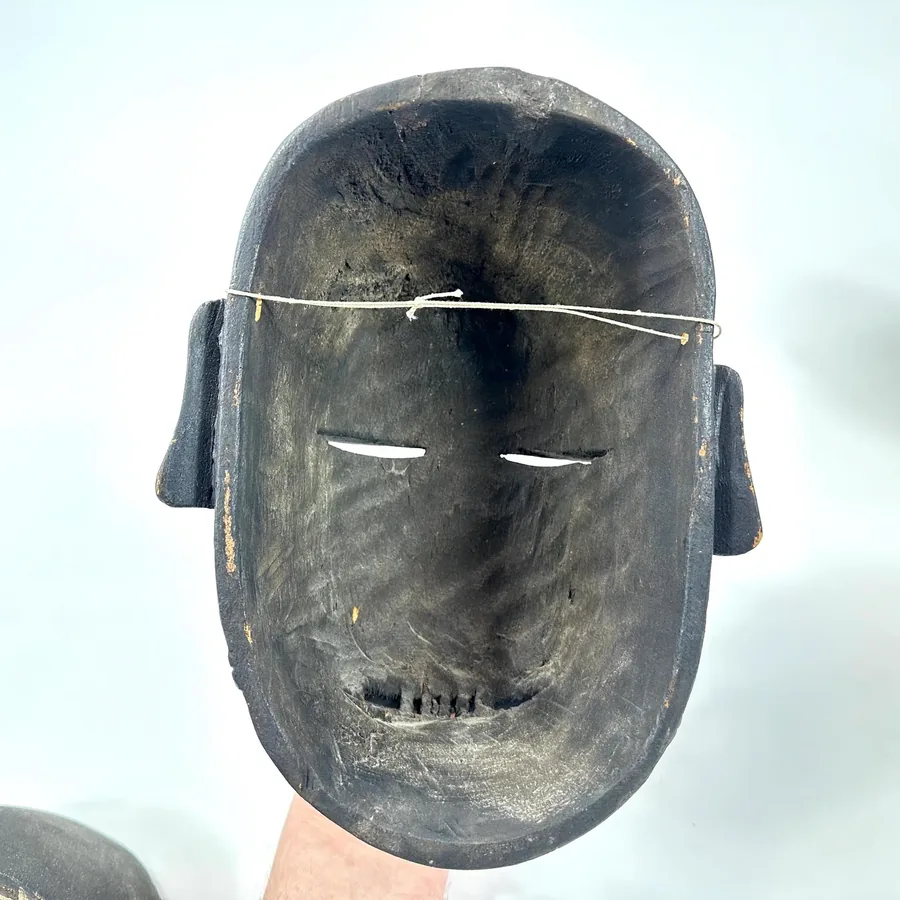 Top-down view of vintage wooden mask showing carved ridge, minimal eye slits, and geometric forehead incisions
