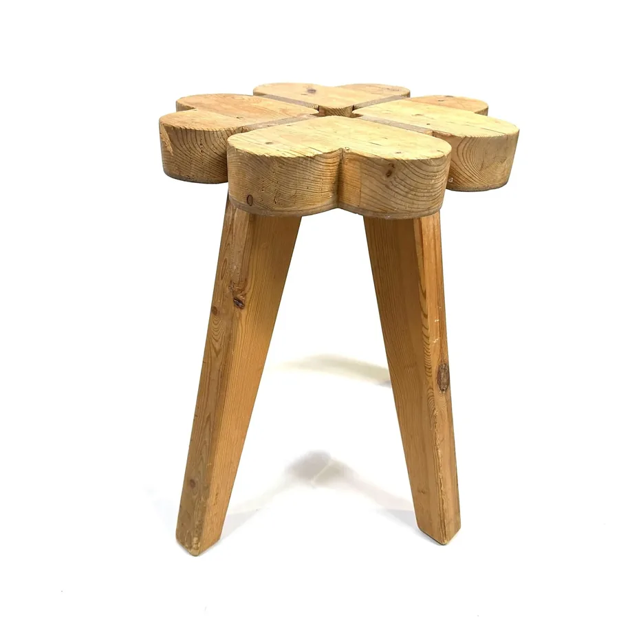 Top-down view of wooden stool showing rounded clover-form seat profile with four tapered legs beneath