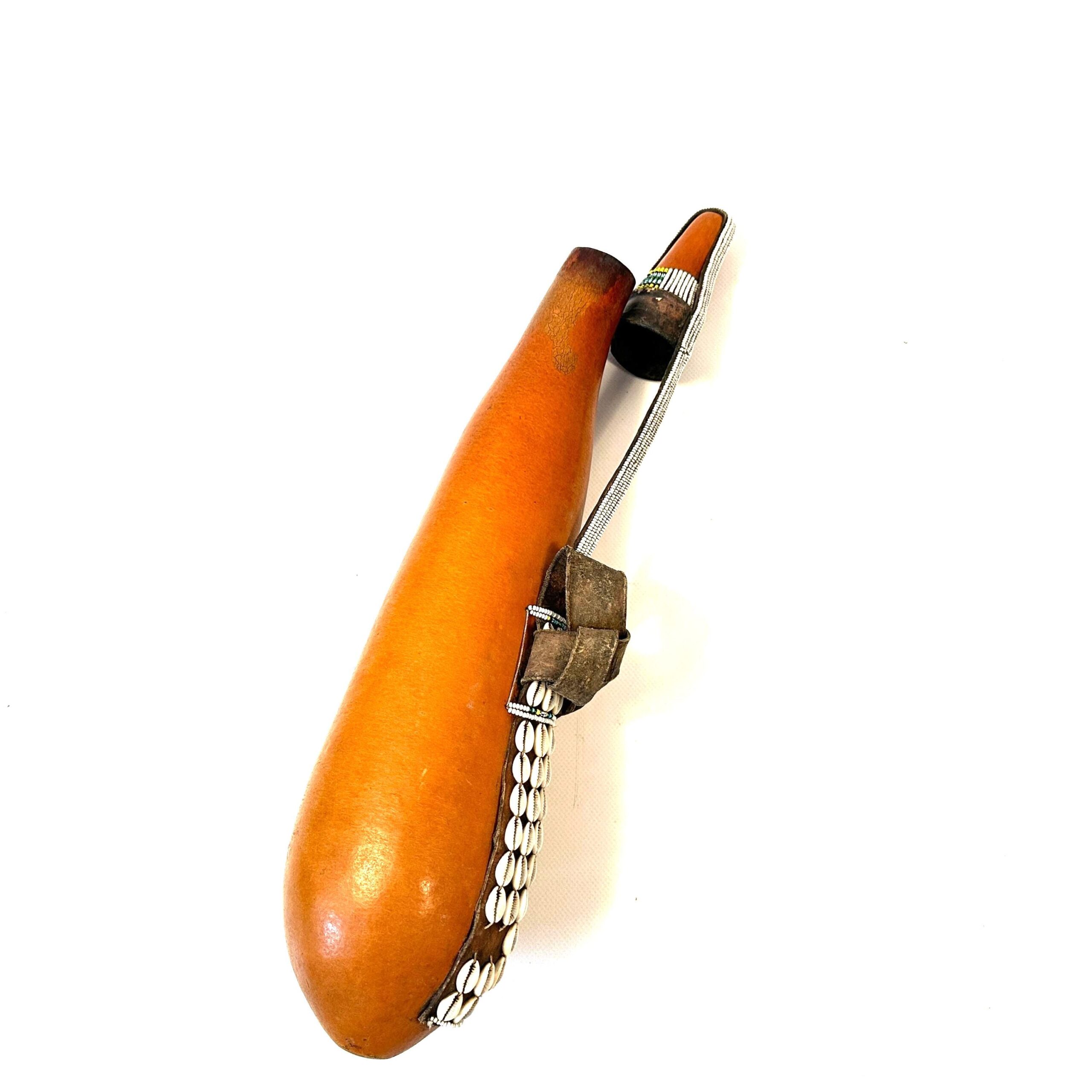 Tribal gourd container horizontal view, leather carrying strap detail, burnished wood surface, metal hardware closeup