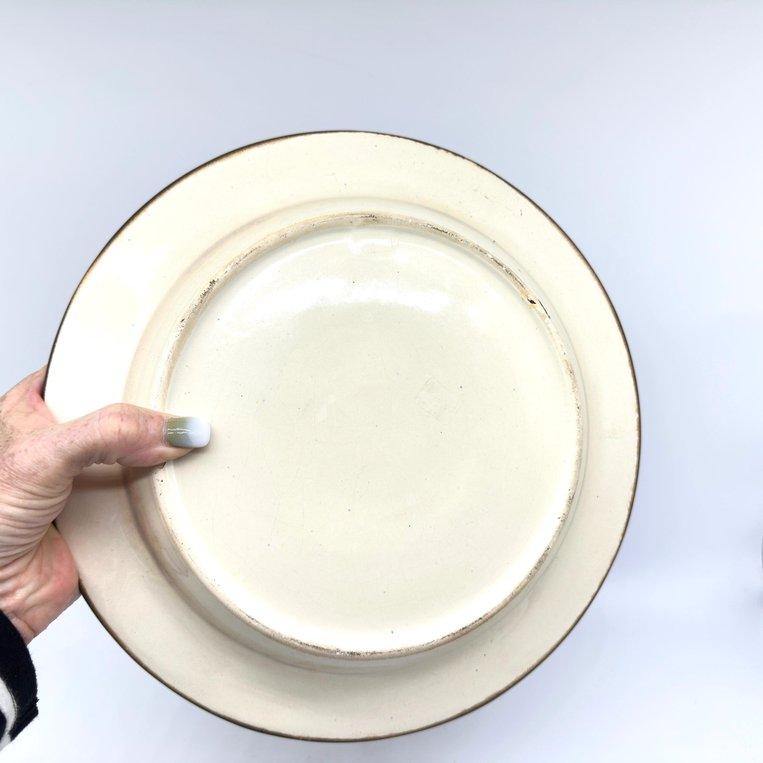 Underside bowl base, cream glaze interior smooth finish, shallow well center, clean ceramic construction