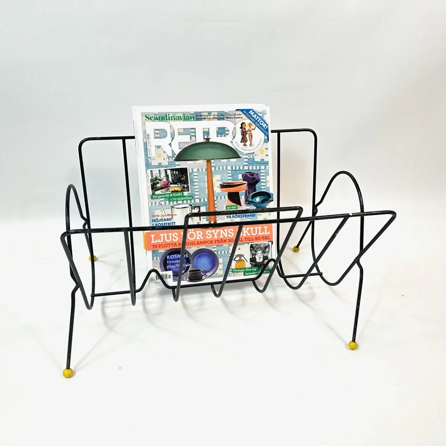 Vintage 1960s wire magazine rack loaded with magazines showing practical storage capacity and space-age design in use