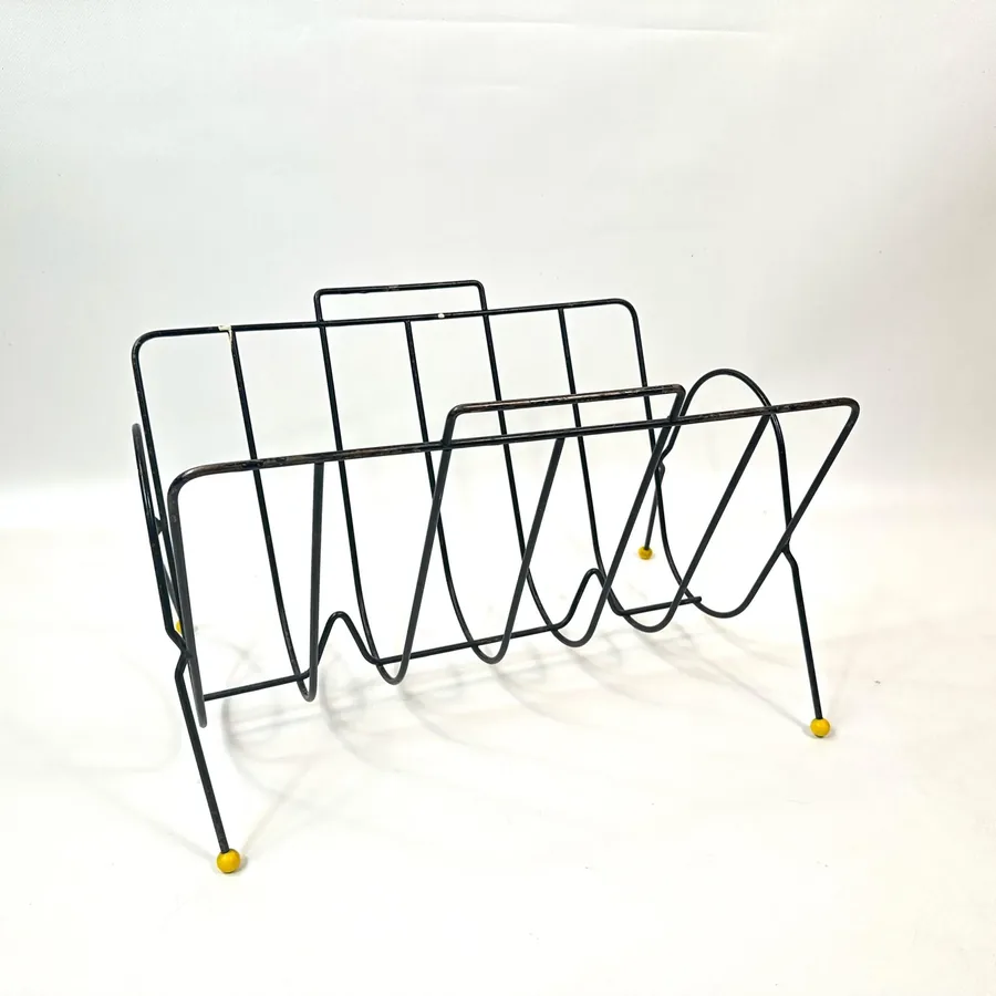 Vintage wire magazine rack angled view displaying black metal framework with multiple compartments and support structure