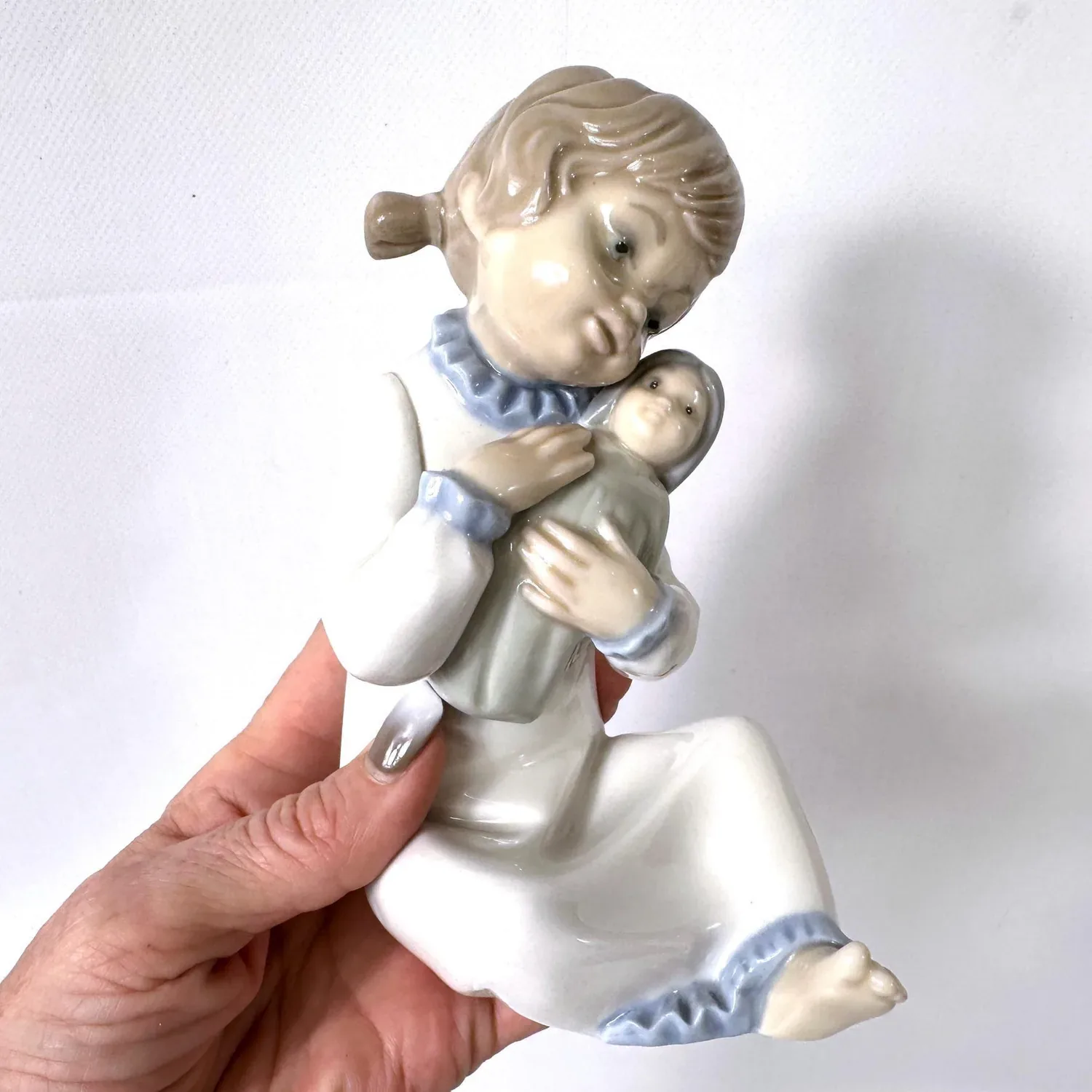 Zaphir Spain porcelain girl figurine in cream gown with blue accents, holding small doll, held in hand to show scale