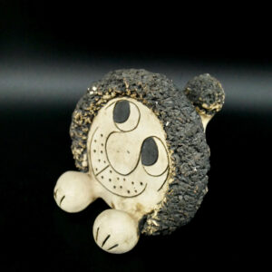 John Hughes Welsh pottery lion figurine with textured charcoal head, cream ceramic body, and hand-drawn smiling face