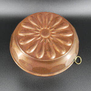 Vintage copper jelly mold with radiant sunburst relief pattern and brass hanging loop, top view