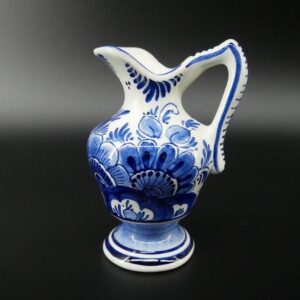 Vintage Delft Blue ceramic creamer jug with hand-painted floral motifs in cobalt and cream, pedestal base, full frontal view
