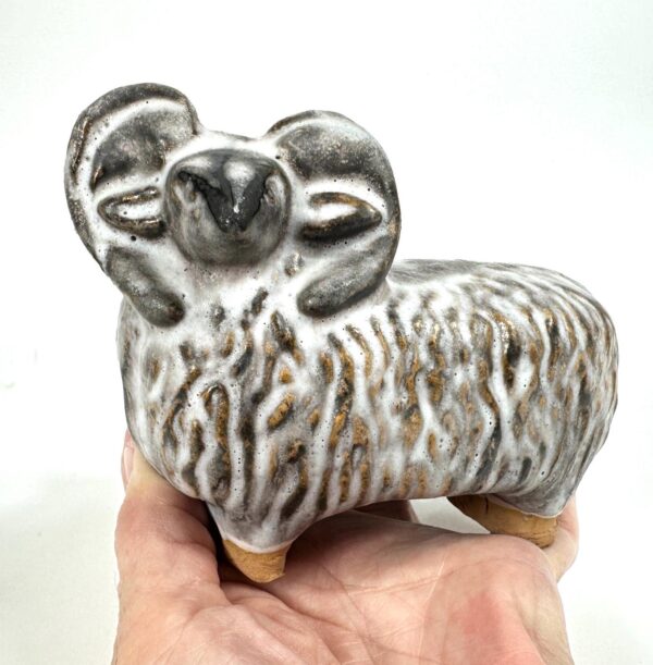 Pottery sheep held in hand showing scale, texture detail, and wooden base construction