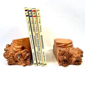 Pair of carved burl wood bookends with vintage books stacked between them, displaying rich honey-brown grain and natural root