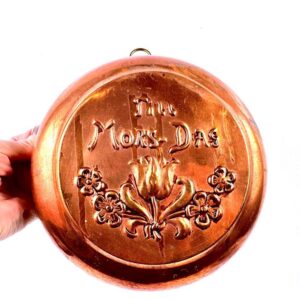 Vintage Scandinavian copper wall plate embossed 'Til Mor-Dag' with floral design, held in hand showing warm patina