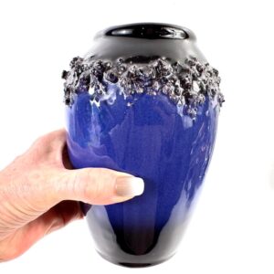 Vintage studio pottery vase with cobalt blue glaze and textured volcanic lava band, held in hand showing scale
