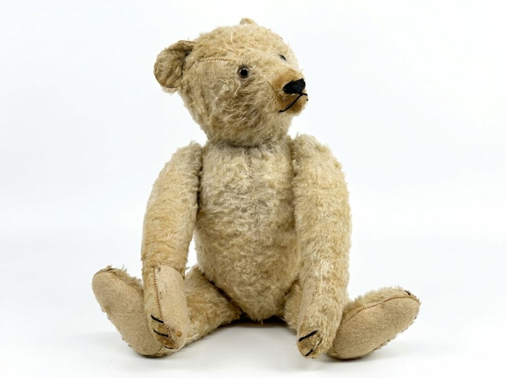 Pale golden teddy bear with jointed limbs and visible seaming, isolated against neutral background showing full body proporti