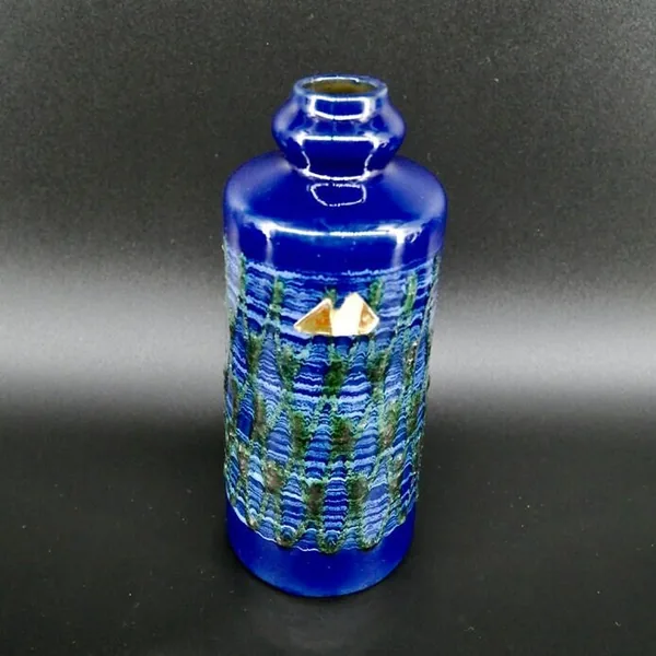 Angled side view of blue ceramic vase with green fat lava pattern and stepped cylindrical form clearly visible